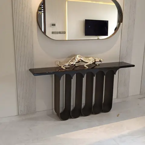 Entrance console styled with a gold leopard statue beneath an oval backlit brass-framed mirror against a fluted stone wall.