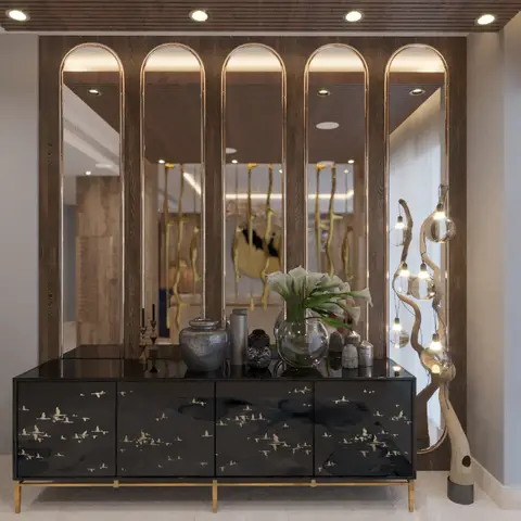 Entrance console vignette with a black lacquered bird-motif cabinet, arched brass-edged mirrors, and a driftwood floor lamp strung with hanging bulbs.