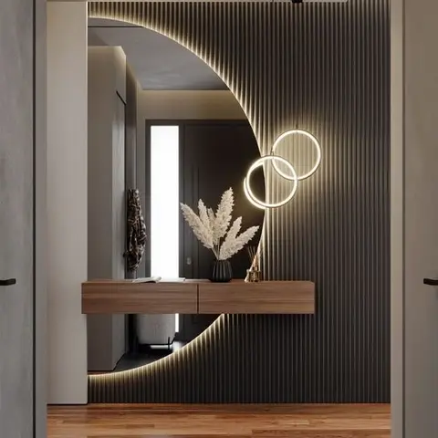 Entrance foyer with a backlit fluted wall panel cut into a crescent moon around a mirror, twin illuminated ring lights