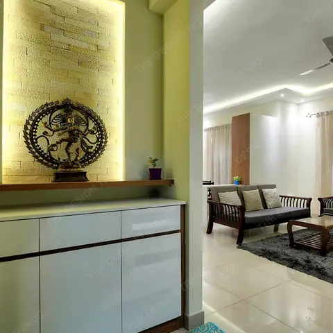 Entrance foyer with a backlit stone-clad niche housing a bronze Nataraja statue above a glossy white console