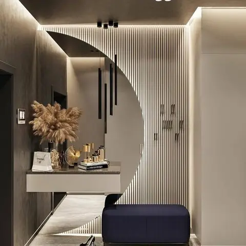 Entrance foyer with a dramatic crescent-moon mirror over a floating console styled with pampas grass, a wood-slat wardrobe wall, and a navy velvet bench.