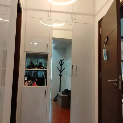 Entrance foyer with a full-height glossy white storage unit, inset display niche and full-length mirror beneath a circular ring pendant light