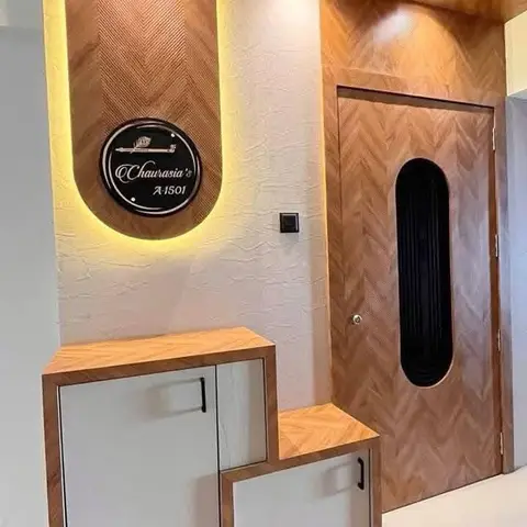 Entrance foyer with a herringbone-pattern wood main door with an oval black glass insert, a backlit nameplate, and a stepped two-tier shoe cabinet.