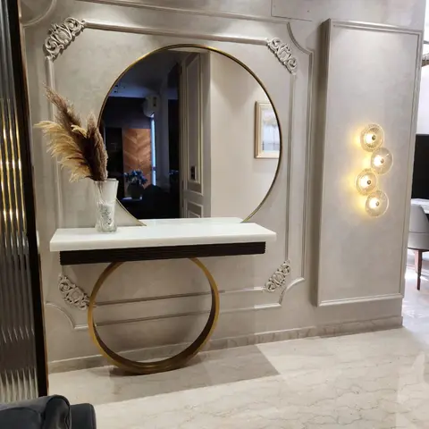 Entrance foyer with a large round gold-framed mirror set into an ornate carved wall moulding panel