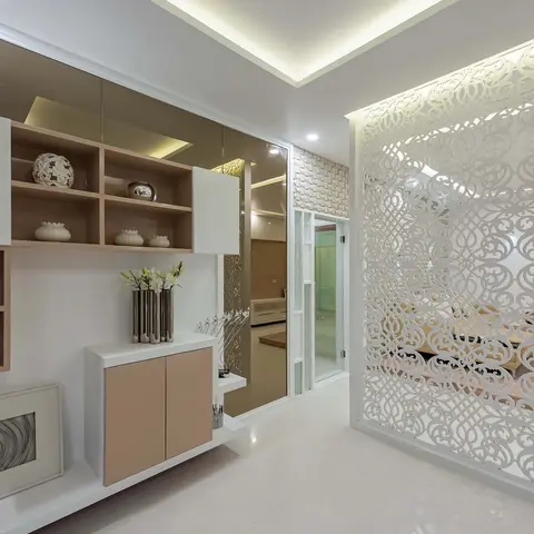 Entrance foyer with a large white laser-cut jaali screen partition on one side and a floating display wall unit with mixed-finish shelving styled with ceramic