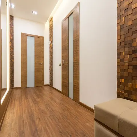 Entrance foyer with a mosaic wood-block feature wall, mirrored wardrobe front and an upholstered bench for seating