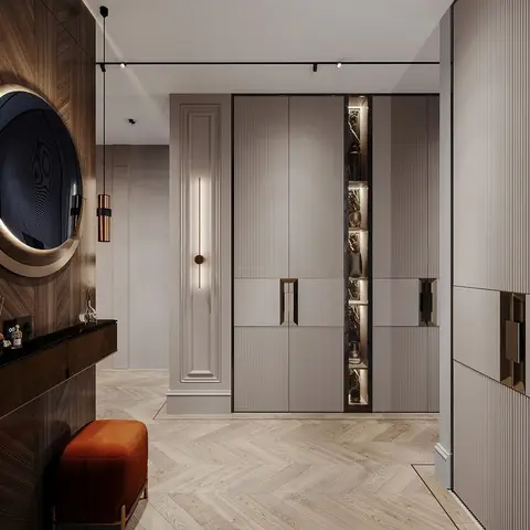 Entrance foyer with a round mirror over a dark wood console, a rust velvet ottoman, a fluted wardrobe wall with a lit glass display niche