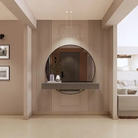 Entrance foyer with a round mirror over a floating fluted-panel console table, framed black-and-white art on the side wall.