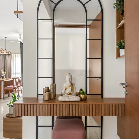 Entrance foyer with a tall arched black-framed mirror above a fluted wood console styled with a Buddha statue and wooden candle holders
