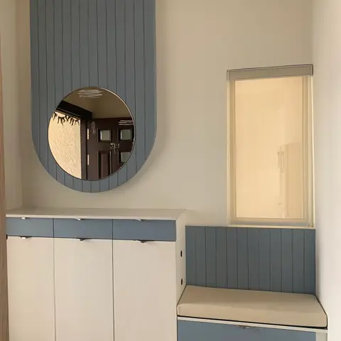 Entrance foyer with a two-tone slatted shoe cabinet, an arched wall-panel mirror and a cushioned storage bench by the window