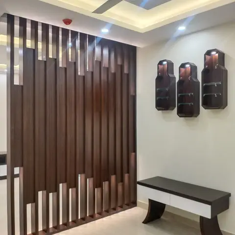 Entrance foyer with a variable-height wood-slat jaali partition, three hexagonal wall-mounted display niches with glass shelving