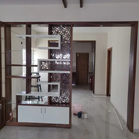 Entrance foyer with a walnut-and-white room divider unit featuring a laser-cut jaali panel and open display shelving
