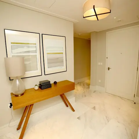 Entrance foyer with a wood tripod-leg console table styled with a lamp and objets, a pair of framed abstract prints