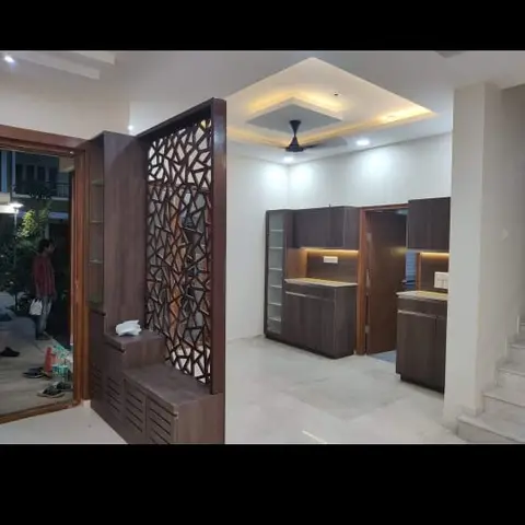 Entrance foyer with an organic branch-pattern wood jaali partition screen and built-in shoe-cabinet steps