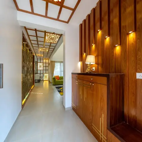 Entrance foyer with the etched-glass teak main door swung open onto a shoe cabinet inlaid with brass line-work