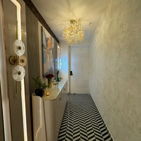 Entrance hallway with a black-and-white marble herringbone floor, a curved cream console table styled with flowers