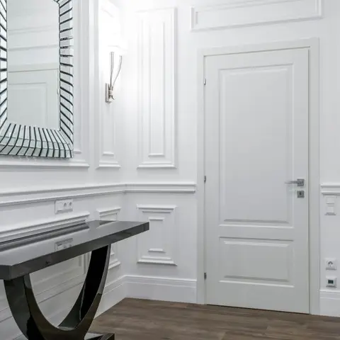 Entrance hallway with full-height white wainscot panelling, a glossy black console table, a faceted mirror and dark wood flooring.
