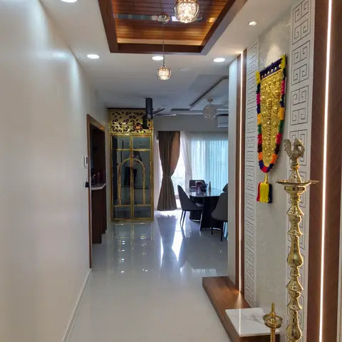 Entrance nook with a backlit geometric jaali wall panel, a marble-topped console styled with brass oil lamps and a traditional torana wall hanging