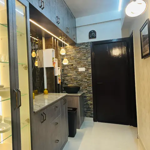 Entrance passage with a stacked-stone clad wash counter, black vessel sink, glass-front crockery display cabinet, and a glossy black main door, shot at a tilt.