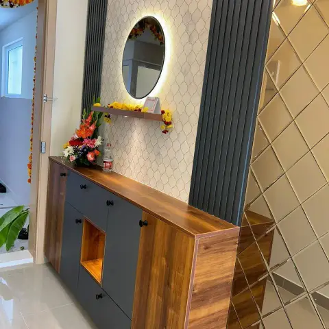 Entry console-cum-shoe unit in teak laminate and charcoal shutters with black knobs, backed by an arabesque mosaic strip