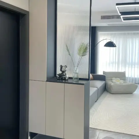 Entry console in greige handleless shutters set in a charcoal frame, topped with a chrome bear figurine and a fern sprig in a ribbed vase