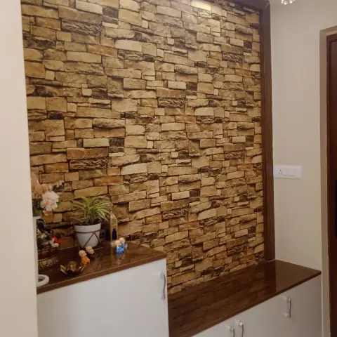 Entry console of white shutters under a glossy wood top runs along a ledge-stone cladding wall framed in dark veneer