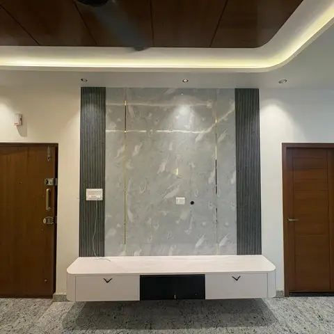 Entry-facing living room wall with book-matched grey marble cladding flanked by fluted panelling