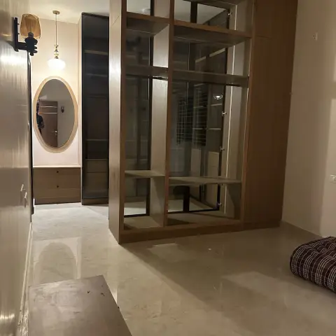 Entry foyer screened by a full-height oak-framed open display unit with a mirrored back
