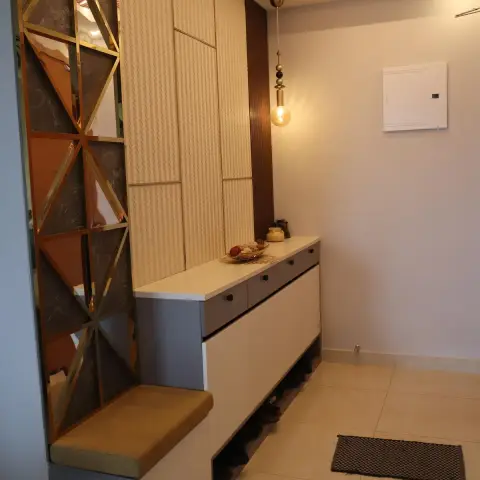 Entry foyer with a brass-grid screen infilled with bronze mirror and brown marble triangles
