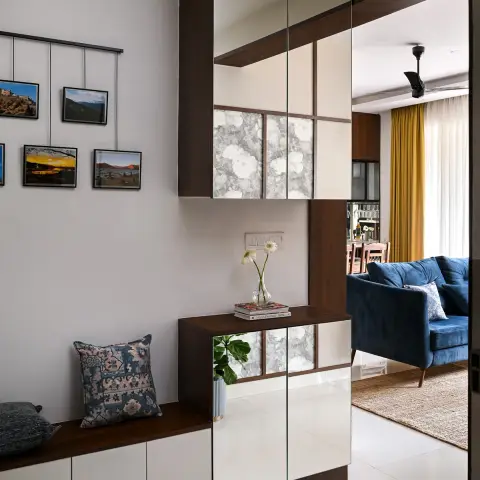 Entry foyer with a walnut-and-white shoe bench running along the wall under a suspended gallery of six framed travel photographs