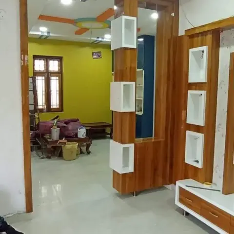 Entry foyer with a wood-veneer partition unit with white cubby shelving separating the entrance from a mustard-yellow living room beyond.
