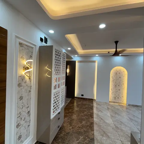 Entry hallway with a jaali-front shoe cabinet beside a floral-wallpapered wall niche lit by sculptural LED sconces
