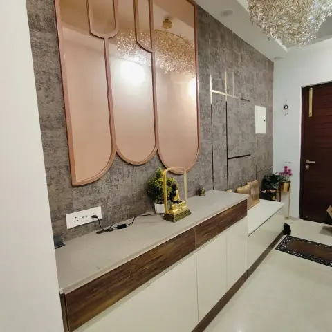 Entry lobby where three rose-gold arched mirror panels sit on a grey stone-look panelled wall above a white-and-walnut shoe console styled with a brass Buddha