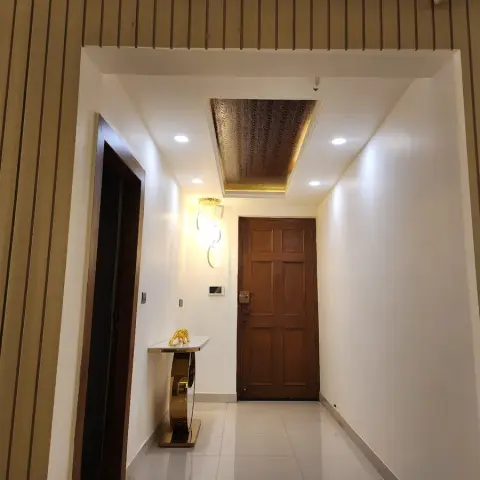 Entry vestibule framed by tan fluted panelling on both flanking walls, a six-panel teak main door at the far end