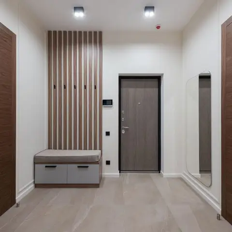 Entryway with a fluted wood-panel feature wall with coat hooks, a cushioned shoe-storage bench, and a full-length mirror beside the main door