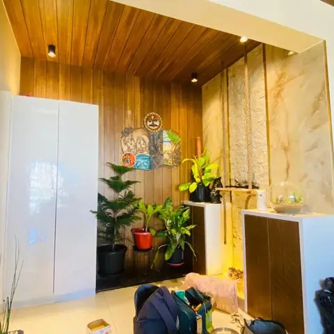 Entryway with a wood-clad ceiling, a glossy white shoe cabinet, potted plants, and a marble-effect wall panel with hanging rope decor