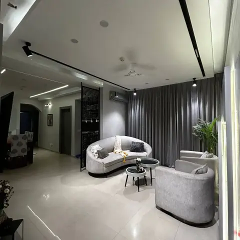 Evening living room in greys where a curved three-seater and two barrel swivel chairs gather around black-topped nesting tables
