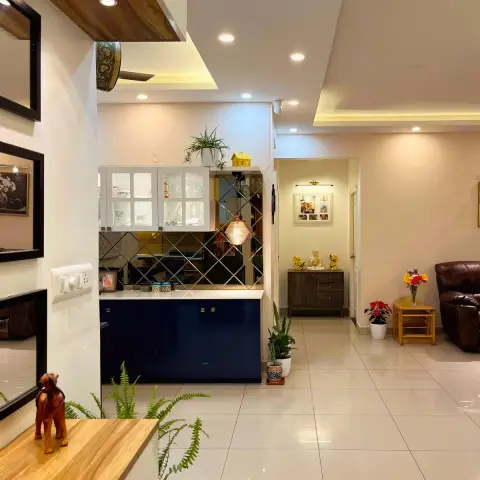 Evening photo across a flat from the dining side: a navy blue pantry counter with white glazed uppers against a bevelled bronze mirror backsplash under a