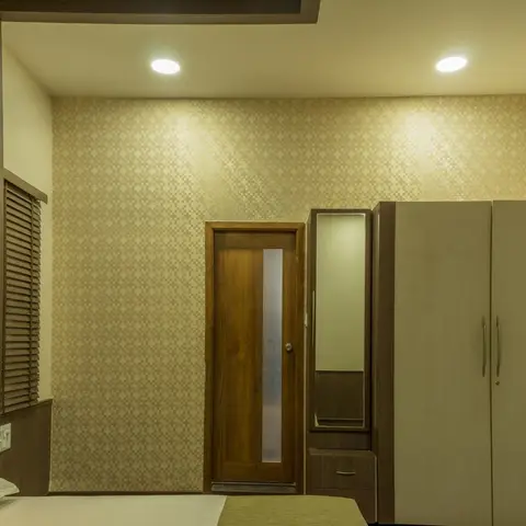 Evening shot of a bedroom with beige pixel-motif wallpaper, a teak flush door with a frosted glass strip