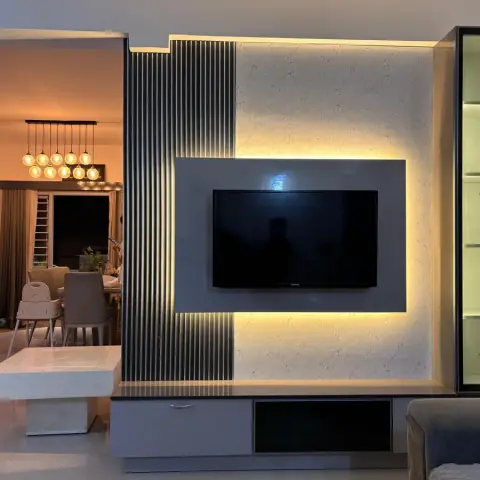 Evening shot of a grey TV wall combining a fluted vertical panel with a backlit marble-look field