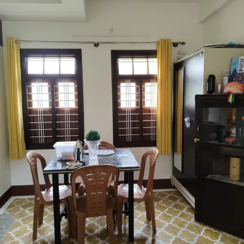 Everyday dining corner with a granite-topped table and moulded plastic chairs on ochre quatrefoil floor tiles