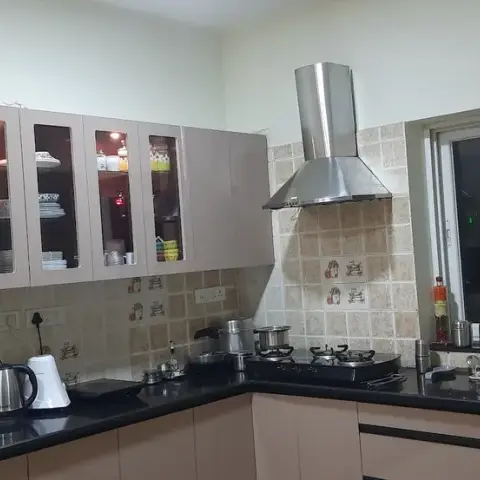 Everyday L-shaped kitchen with dusty-rose gloss shutters, internally-lit glass-front crockery cabinets