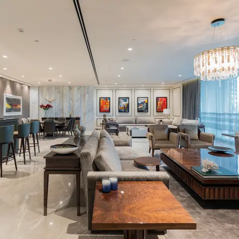 Expansive living room with grey upholstered sectional sofas around a glossy dark-wood coffee table, a tiered crystal drum chandelier and a marble feature wall