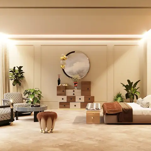 Expansive master bedroom with a patterned lounge seating area, a sculptural chest of drawers beneath a round gold-accented mirror