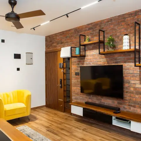Exposed-brick TV wall hung with black-framed floating wood shelves and a live-edge timber console