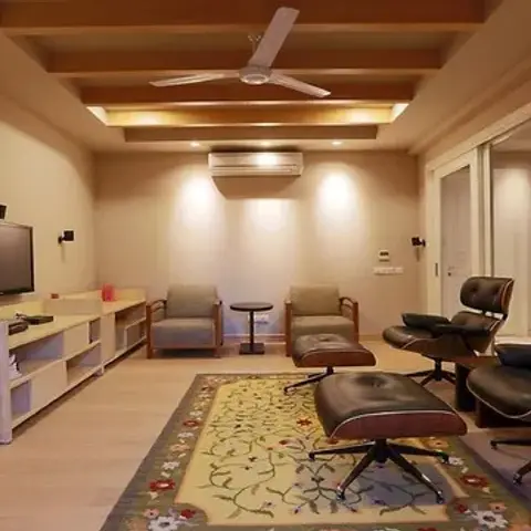 Family den with exposed timber ceiling beams, a pair of black leather lounge chairs and ottomans on a floral border rug