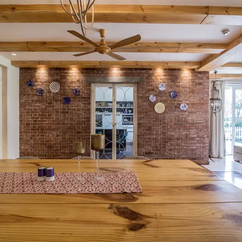 Farmhouse-style dining space with a solid wood plank table, an exposed brick accent wall styled with decorative plates