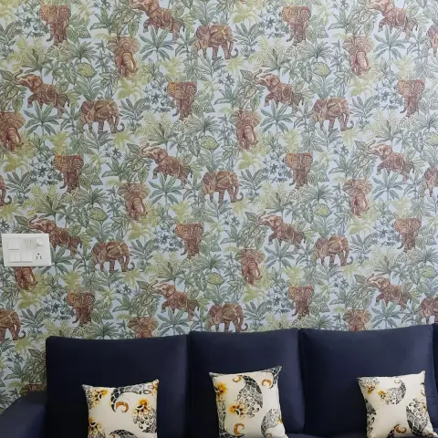 Feature wall papered with caparisoned elephants among pale green foliage, filling the wall above a navy three-seater sofa dressed with three cream paisley