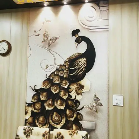 Feature wall with a large gold-and-black peacock mural wallpaper under a gold-patterned ceiling drop with spotlights, floral-upholstered ottomans in front