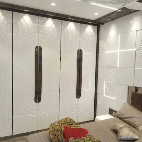 Five-shutter high-gloss white wardrobe with routed concentric-oval grooves and slim dark inset handles, washed by ceiling spots